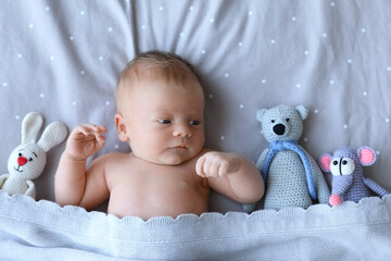 Poster - Cute newborn baby with toys in bed, top view