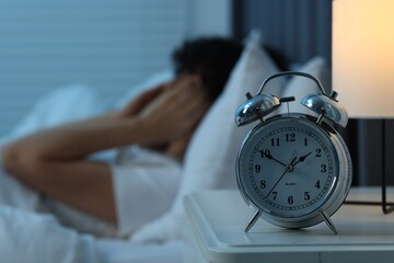 Wall Mural - Woman suffering from headache in bed at night, focus on alarm clock