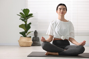 Sticker - Beautiful girl meditating on mat in yoga studio