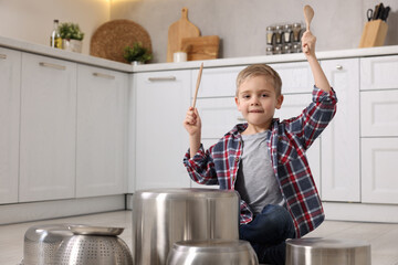 Poster - Little boy pretending to play drums on pots in kitchen