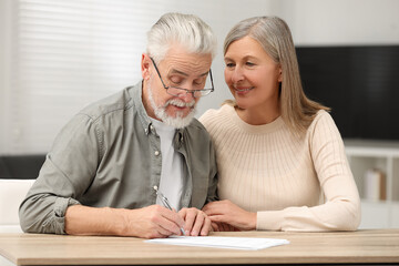 Canvas Print - Senior couple signing Last Will and Testament indoors