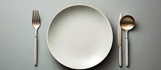 Sticker - A porcelain plate with cutlery placed neatly on a table. The silverware shines against the white dishware, creating an elegant setting