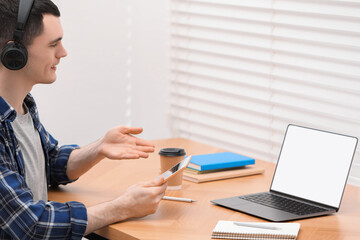 Wall Mural - E-learning. Young man using laptop during online lesson at table indoors.