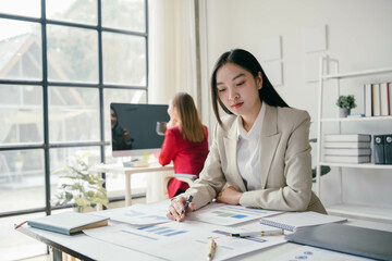 Wall Mural - A woman in a business suit is sitting at a desk with a computer monitor