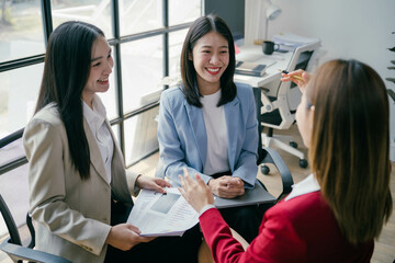 Poster - Three women are sitting in a conference room, smiling and talking to each other