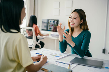 Poster - Two women are sitting at a desk talking