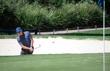 Wall Mural - Golfer hits ball from a bunker with golf club