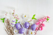 Happy easter holidays concept; Artificial twigs with white and pink apple blossom and easter eggs on a white paint wooden background; copy space
