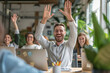 © BrightSpace - Successful teamwork in the corporate office brings happiness, A group of people are smiling and waving at the camera. The man in the center is the only one with a beard