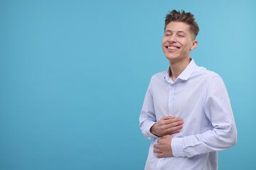 Poster - Young man laughing on light blue background. Space for text