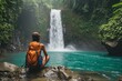 A person sits on a rock, gazing at a majestic waterfall surrounded by lush greenery, A backpacker pausing to appreciate a stunning waterfall located in dense forest, AI Generated