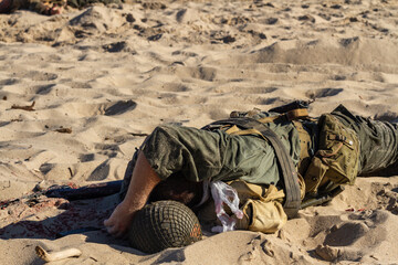 Historical reconstruction. Injured or dead World War II infantry  soldier  on the beach. View from the back.  Hel, Poland