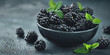 Summer sweet dessert, a bunch of juicy blackberries in a bowl on a gray background