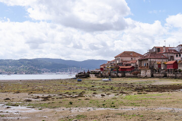 View of the town of Combarro in Galicia from the shore of the estuary. Landscape with cloudy sky and the village on the estuary.