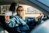 Fototapeta Mapy - woman showing her new driver license while sitting in car. driving school
