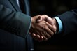 © Alice O - Close-up of a firm handshake between two business professionals in a dark setting, symbolizing trust and agreement.