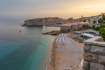 Wall Mural - Sunset landscape with Banje beach and old town of Dubrovnik, Dalmatia, Croatia. Medieval fortress on the sea coast. Popular travel destination. Summer vacation background