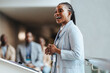 © Jacob Lund - Young African businesswoman speaking at a conference with colleagues in background