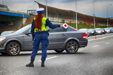 Fototapeta  - Policjantka ruchu drogowego z lizakiem podczas zatrzymania pojazdów na drodze z tarczą do zatrzymywania.
