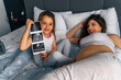 © DusanJelicic - Girl shows ultrasound while mom lies on the bed next to her, excited to be a big sister.