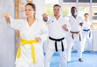Sedulous middle-aged female practitioner of karate courses performing fighting positions during training session