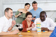 © JackF - Multiethnic group of emotional people excitedly playing Jenga at home