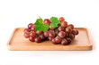 Red grapes with leaves on wooden tray on white background.