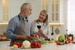 © New Africa - Happy senior couple cooking together in kitchen. Woman with glass of wine near her husband