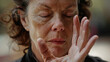 A closeup of a womans face eyes closed in concentration as she performs a Tai Chi move known for its calming effect on the mind.