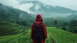 The back of a young man wearing a red hood Walking on terraced rice fields With a magnificent view of Sao Yokarn Mountain