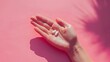 Hand Holding White Pill on Pink Background - Healthcare and Medicine Symbol