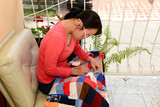 Fototapeta  - Portrait of a girl with down syndrome knitting a blanket on the balcony of her house.
