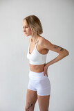 Fototapeta  - Blonde girl posing on a white background in a top and leggings
