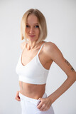 Fototapeta  - Blonde girl posing on a white background in a top and leggings