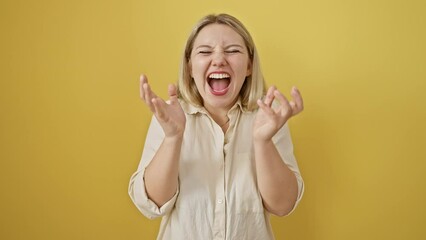 Sticker - Excited young blonde woman stands victoriously, celebrating win in mad, crazy triumph! pure joy, winner's gesture, arms uplifted, isolated on yellow background.