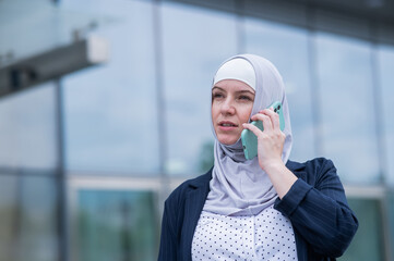 Business woman in hijab and suit talking on smartphone. 