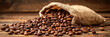 coffee beans spilling out of the burlap bag on wooden background. banner