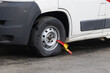 A yellow and red parking claw secures the tyre of a parked motorhome
