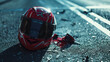 A detailed shot of a red motorcycle helmet on a road during sunset indicating an accident
