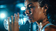 A sports woman takes a refreshing sip of water from a bottle after workout. Her face glowing with exertion. The importance of hydration in sports and fitness. Generative AI.