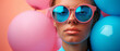 A young woman with oversized pink sunglasses surrounded by colorful balloons on a blue backdrop