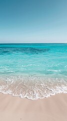 Poster - A sandy beach with crystal clear blue water stretching out to the horizon under a bright sunny sky. Waves gently lapping at the shore, creating a serene atmosphere.