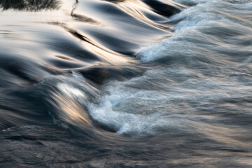 Rapid water flows in stream over stony bottom making cascades - abstract landscape close up