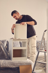 Wall Mural - Man working and assembling furniture in a new apartment.