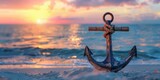 Vintage anchor on sandy beach with beautiful sunset over the ocean in the background.