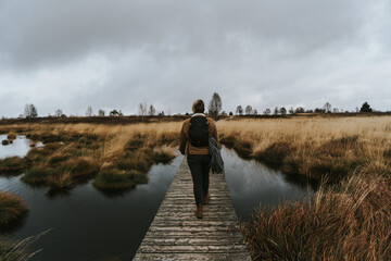 Person walking on wooden pathway on lake in outdoor moody environment