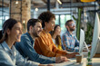 © BrightSpace - business group of people are sitting at a desk with computers and smiling. Scene is happy and friendly,A cheerful group sits at desks with computers, smiling