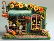 Handcrafted felt miniature cafe house with vibrant floral accents and a cozy outdoor setting. Artistic close-up of a whimsical cottage perfect for storytelling and home decor