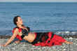 beautiful dancer woman in black and red suit lays by seashore