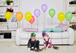 © Pavel Losevsky - two children playing with kittens on background of room with big soft white sofa, light carpet on floor and row balloons hanging in air